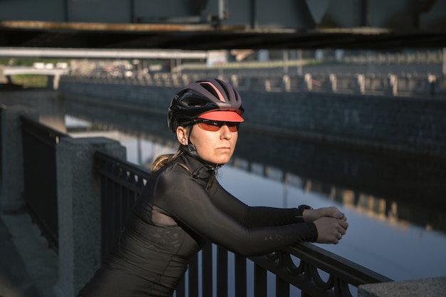 Cycliste d'athlète posant sur le remblai de ville au coucher du soleil