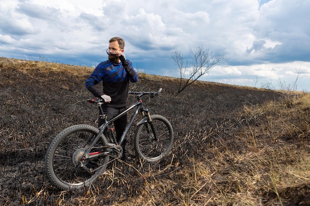 Cycliste barbu sur un vélo de montagne sur un champ brûlé