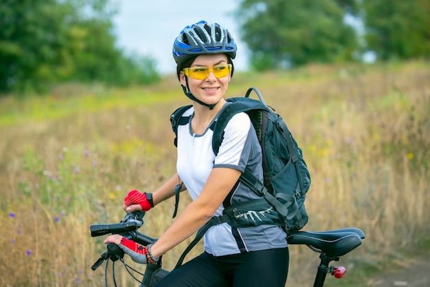 Cycliste de belle femme avec un vélo sur la nature. Mode de vie sain et sport. Loisirs et passe-temps