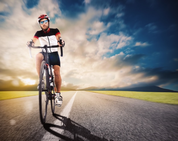 Cycliste avec casque pédalant plus vite sur route