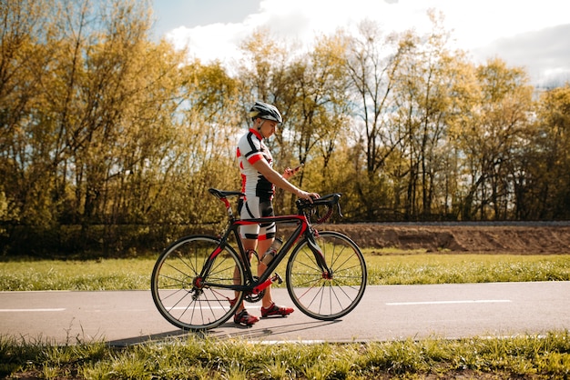 Cycliste en casque et vêtements de sport, entraînement de cyclocross sur route asphaltée.