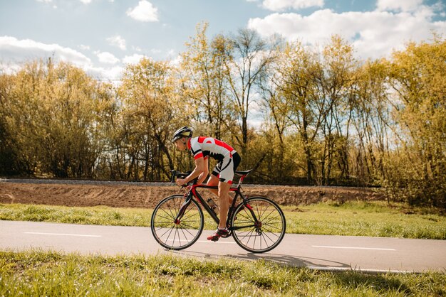 Cycliste en casque et vêtements de sport à vélo, vue latérale.