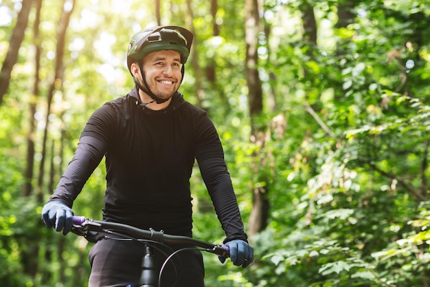 Cycliste masculin joyeux faisant du vélo dans la forêt de montagne