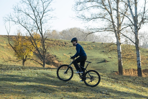 Cycliste en pantalon et veste polaire sur un vélo semi-rigide en carbone moderne avec une fourche à suspension pneumatique tout-terrain