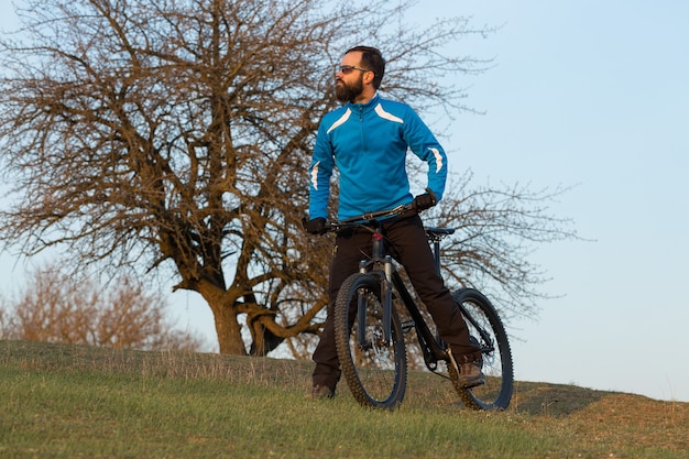 Cycliste en pantalon et veste polaire sur un vélo semi-rigide moderne en carbone avec fourche à suspension pneumatique