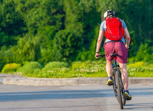Cycliste pédalant sur un vélo de course à l'extérieur. L'image du cycliste en mouvement sur l'arrière-plan pendant la journée d'été.