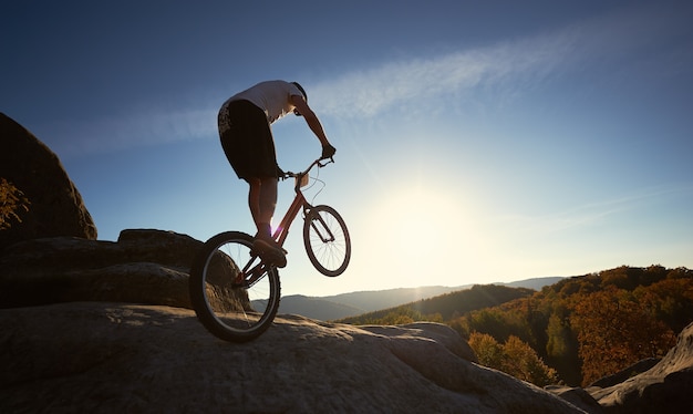 Cycliste professionnel en équilibre sur vélo d'essai au coucher du soleil