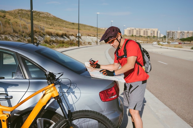 Cycliste regardant la carte d'itinéraire à côté de la voiture