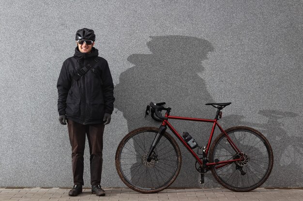 Cycliste se tient près du mur de béton avec vélo