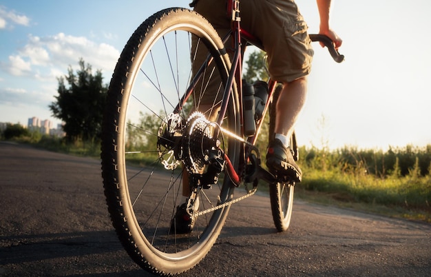 Le cycliste se tient sur la route au coucher du soleil