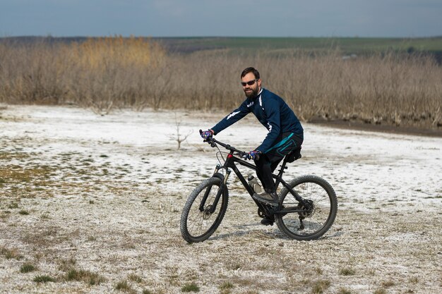 Cycliste en short et maillot sur un vélo moderne avec une fourche à suspension pneumatique debout sur une falaise