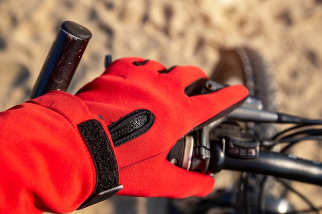 Le cycliste tient le volant dans des gants reposant sur la plage en été