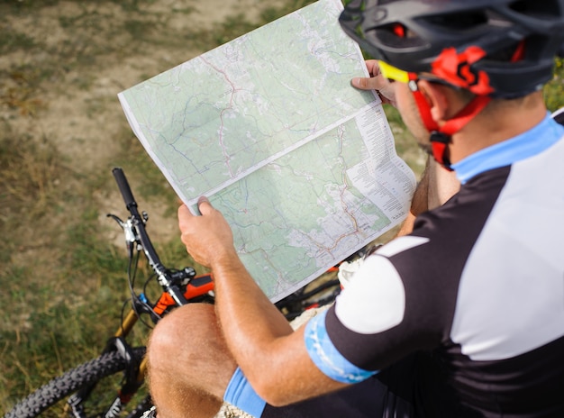 Photo cycliste touristique avec plan de route regardant vers la carte