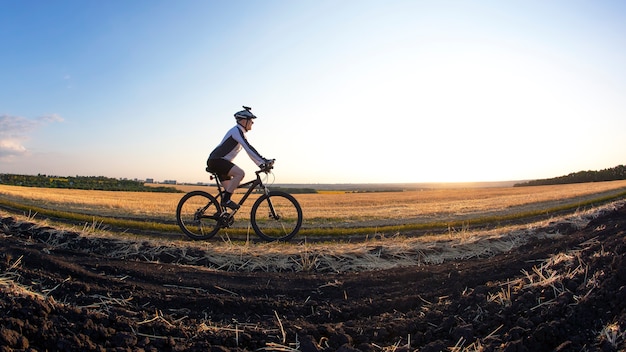 Cycliste à vélo le long des champs de blé au soleil