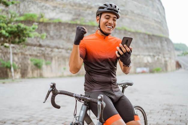 Cycliste de vélo de route assis sur son vélo tout en utilisant un téléphone portable