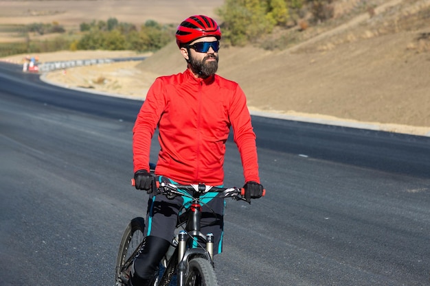 Cycliste à vélo sur route contre un ciel clair Un homme dans une tenue se tient avec un vélo par une journée ensoleillée d'automne