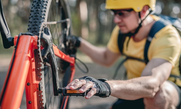 Cycliste vérifiant le défaut de la roue à chaîne sur la bicyclette à l'envers en forêt