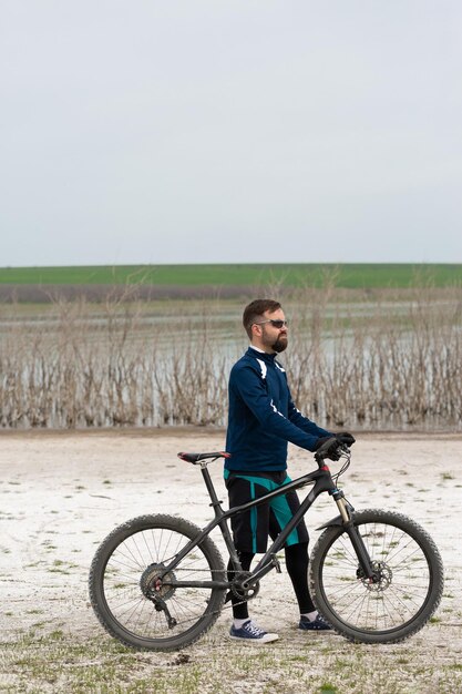 Cycliste en VTT sur une plage de sel sur fond de roseaux et d'un lac