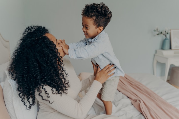 Dame afro-américaine enceinte jouant avec son fils à la maison