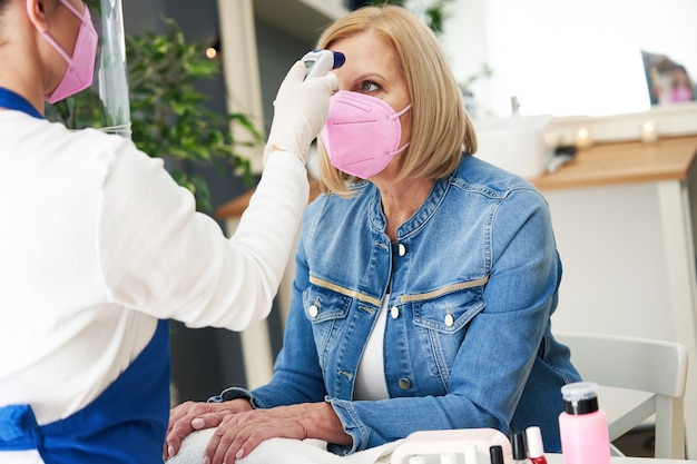 dame âgée portant un masque dans un salon de manucure