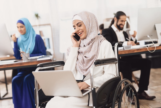 Une dame arabe handicapée en hijab passe un appel d&#39;affaires