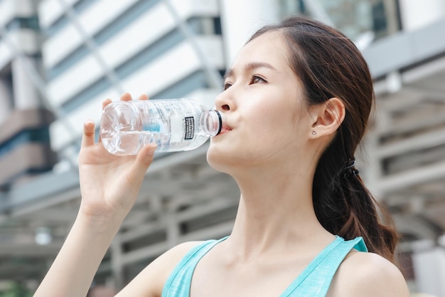 Dame asiatique buvant de l'eau sport mode de vie sain à l'extérieur dans la construction de fond de ville