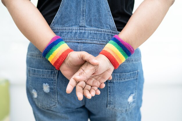 Dame asiatique portant des bracelets de drapeau arc-en-ciel symbole du mois de la fierté LGBT