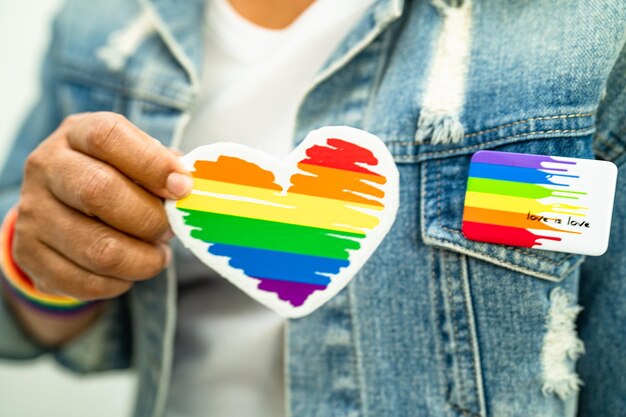 Une dame asiatique portant des bracelets de drapeau arc-en-ciel et tenant un cœur rouge, symbole du mois de la fierté LGBT, célèbre chaque année en juin la société des droits humains des homosexuels, des lesbiennes, des bisexuels et des transgenres.