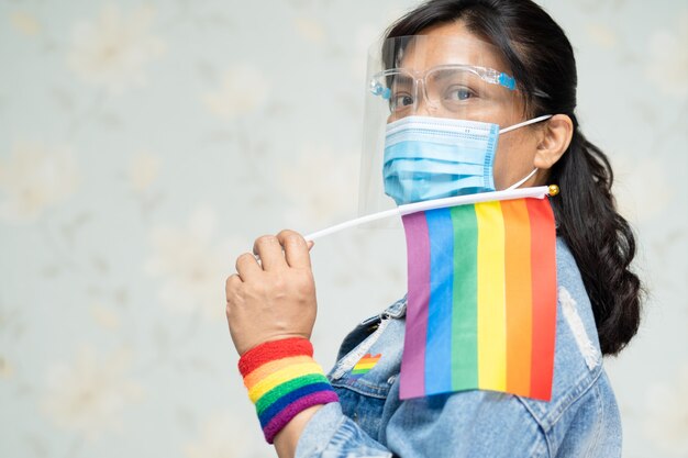 Dame asiatique portant une veste en jean bleu ou une chemise en jean et tenant un drapeau arc-en-ciel, symbole des LGBT.