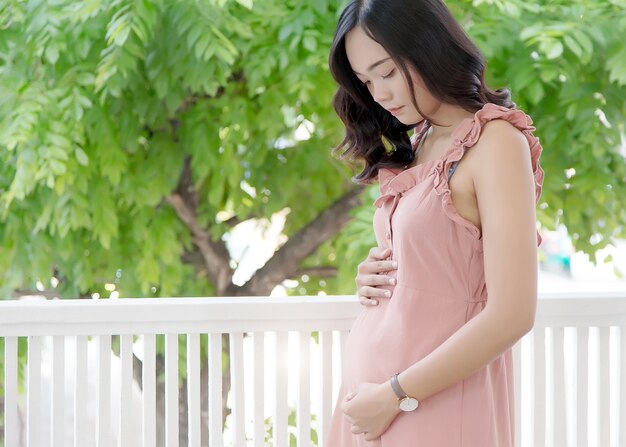 Une dame asiatique porte son stomatch comme le nouveau-né de la grossesse