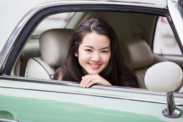 Dame asiatique souriante dans une voiture vintage