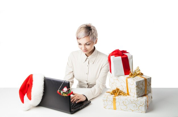 Dame au bureau avec des boîtes à cadeaux et un chapeau sur blanc