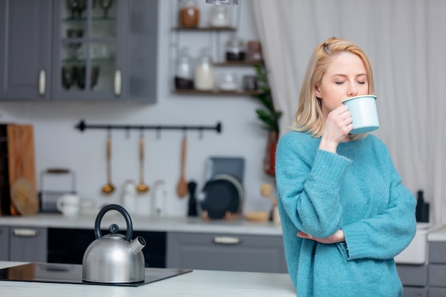 Dame blonde avec une tasse de café à la cuisine