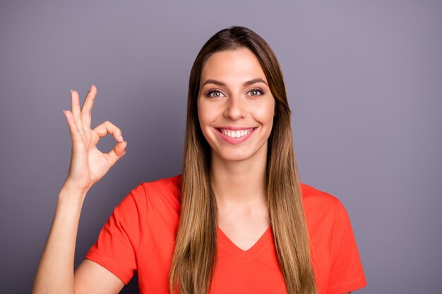 Dame brune en t-shirt rouge posant contre le mur violet