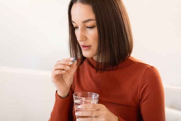 Dame européenne du millénaire prenant un supplément ou une pilule de vitamines à la maison