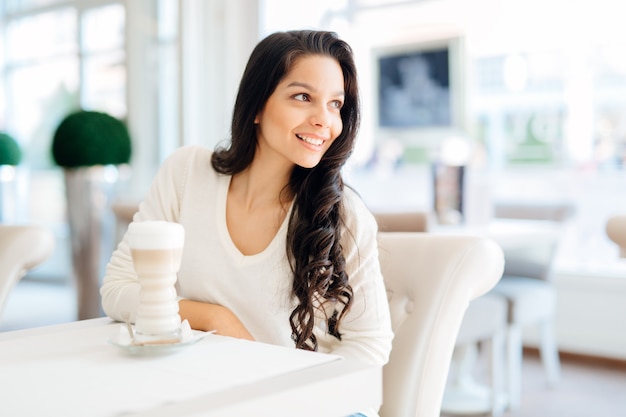 Dame glamour buvant du café dans un beau café