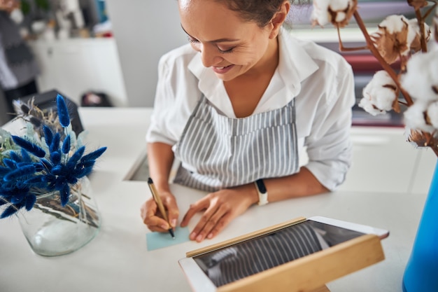 Dame heureuse tenant un stylo et écrivant une note