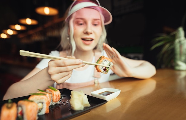 Dame mangeant des sushis dans un restaurant asiatique photo gros plan de sushis dans des baguettes