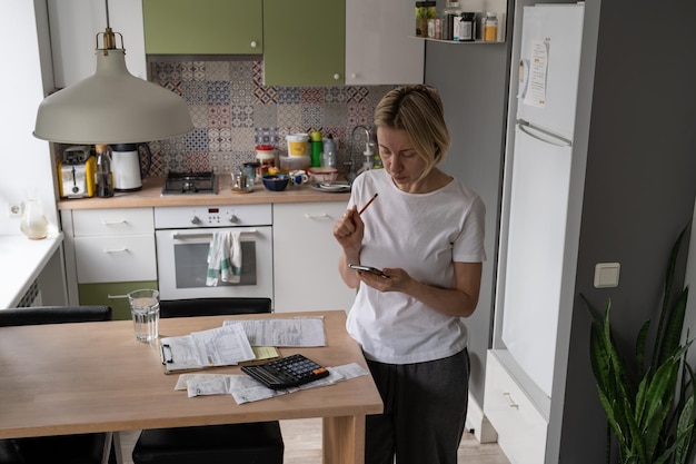 Dame mûre recherche le numéro de téléphone de la hotline pour résoudre le problème des factures d'électricité Budget familial