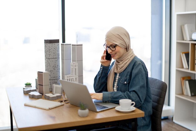 Dame parlant au téléphone et utilisant un ordinateur portable au travail