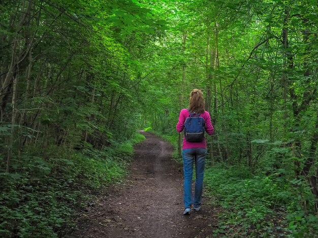 Dame avec sac à dos voyage dans la forêt verte.