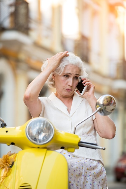 Dame en scooter avec téléphone.