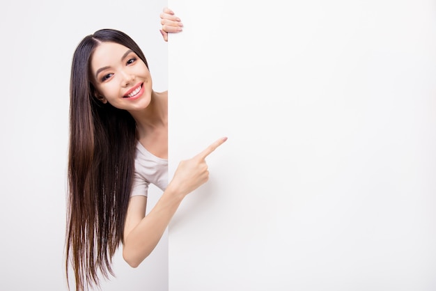 Dame souriante en tshirt blanc s'appuyant sur un panneau d'affichage vide