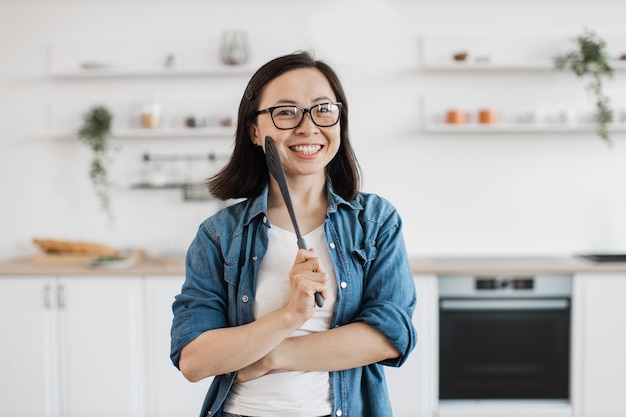 Une dame avec une spatule choisissant des outils de cuisine pour cuisiner à la maison