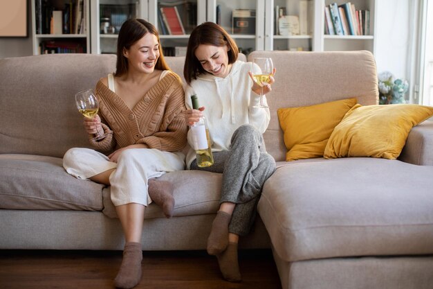 Des dames européennes du millénaire qui rient en chandails avec des verres de bouteille de vin profitent du repos pour se détendre pendant le temps libre