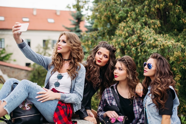 Dames à la mode avec coiffure prenant selfie à l'extérieur.