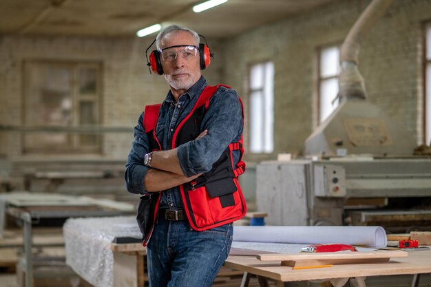 Dans un atelier. Homme mûr à lunettes et protège-oreilles dans un atelier