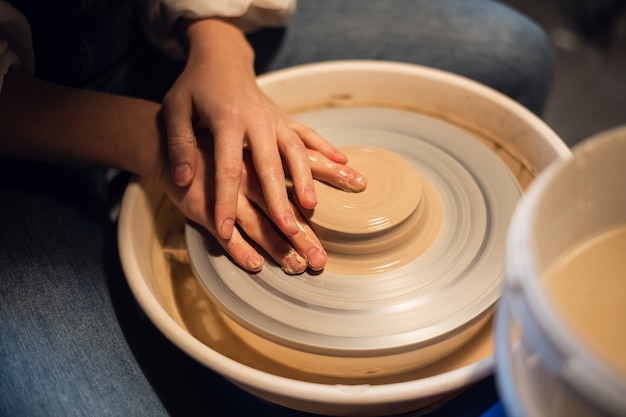 Dans l'atelier, un potier sculpte à la main un vase en argile sur un tour de potier.