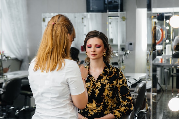 Dans un beau salon de beauté moderne, un maquilleur professionnel maquille une jeune fille. Beauté et mode.