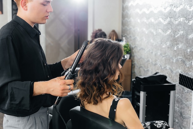 Dans un beau salon de beauté moderne, un styliste professionnel fait une coupe de cheveux et une coiffure pour une jeune fille